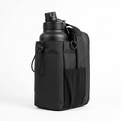 A flattering 3/4 front view of the all-black Aveliques Magnetic Gym Bag holding a large water bottle, with phone and accessory pockets visible, on a pure white studio background.