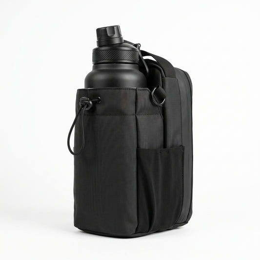 A flattering 3/4 front view of the all-black Aveliques Magnetic Gym Bag holding a large water bottle, with phone and accessory pockets visible, on a pure white studio background.