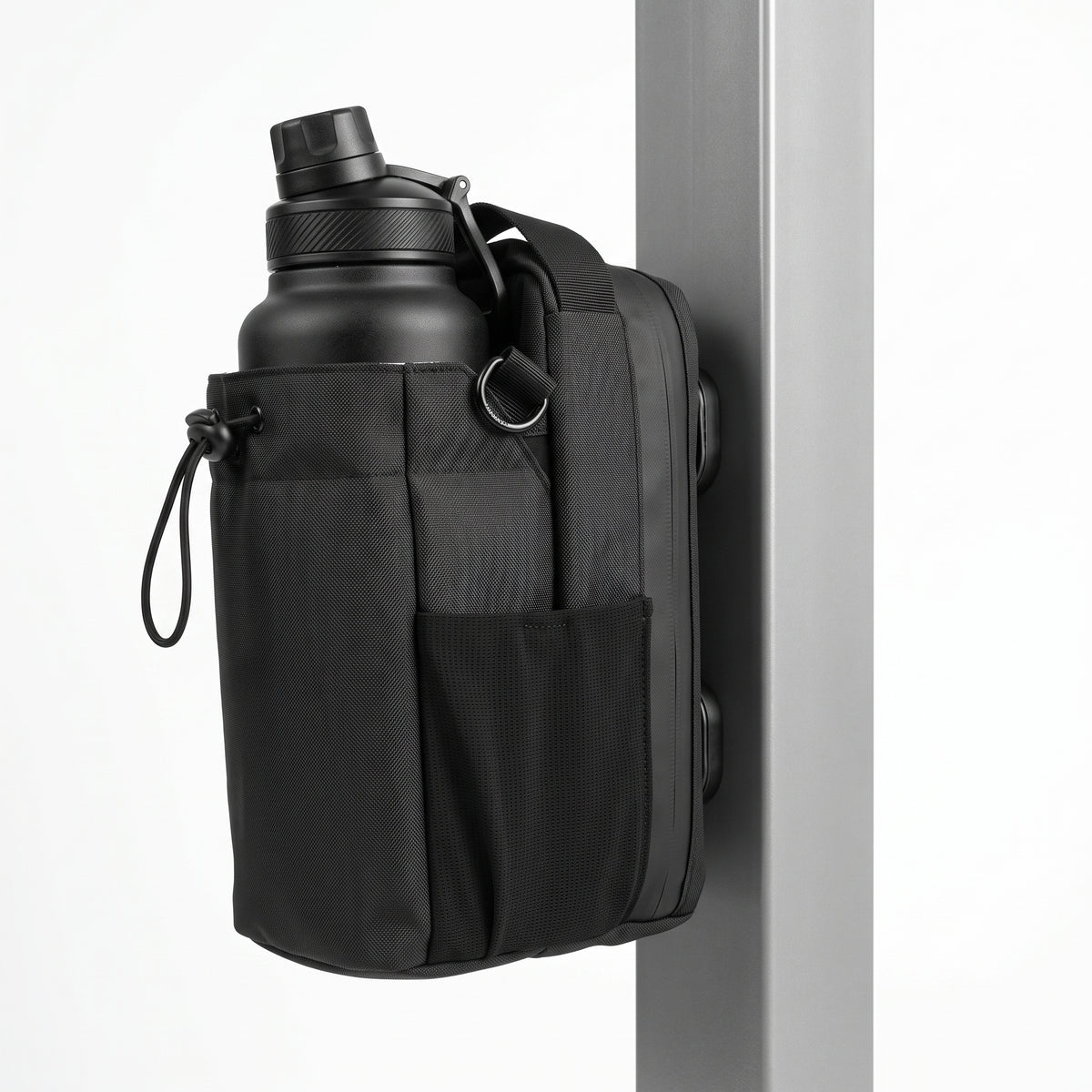 An isometric angled profile view of the black Aveliques Magnetic Gym Bag showing the multiple magnetic plates on the back, temporarily attached to a metal plate, demonstrating its function, on a seamless white background.
